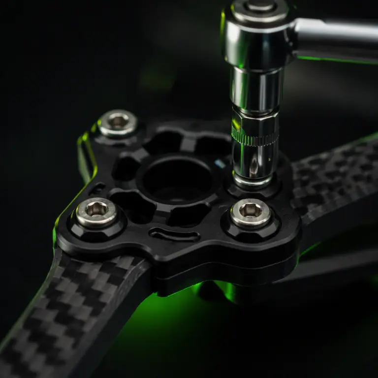 Macro photograph of a machined black anodised aluminium UAV motor mount bolted to a carbon fiber arm with four stainless steel socket-head fasteners, a calibrated torque wrench engaged on one fastener, dark studio background, lime green accent glow, precision aerospace hardware aesthetic, photorealistic, no people faces, no text, no logos