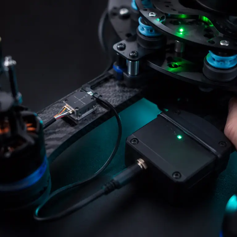 Close-up photograph of a small triaxial accelerometer sensor wired to a data logger and mounted on a UAV motor arm next to a vibration-isolated payload plate, dark test bench, green and teal LED glow, precision measurement equipment aesthetic, photorealistic, no people faces, no text, no logos